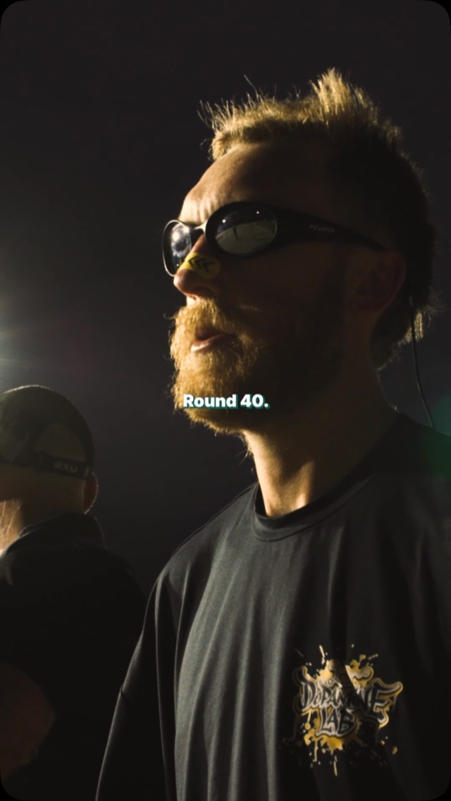 Bearded athlete in sunglasses lit by floodlights at night